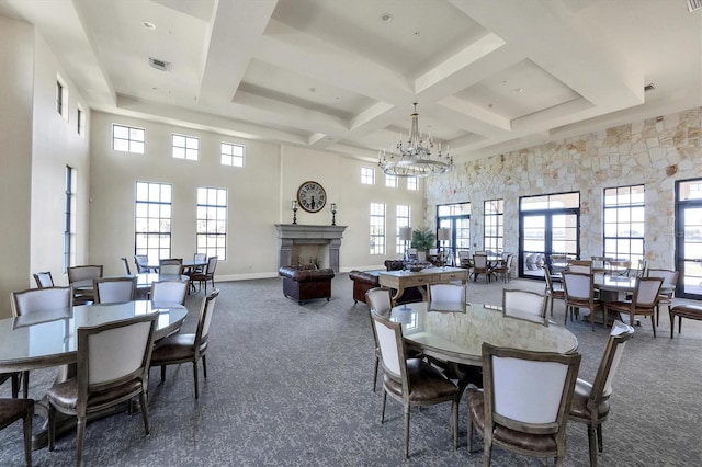 dining room featuring a towering ceiling, a fireplace, visible vents, and dark carpet