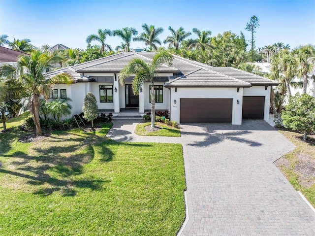 view of front of home featuring an attached garage, a front lawn, decorative driveway, and stucco siding