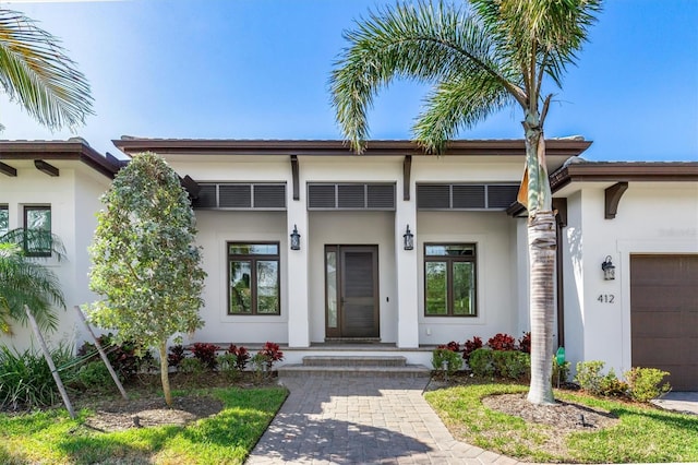 property entrance featuring a garage and stucco siding