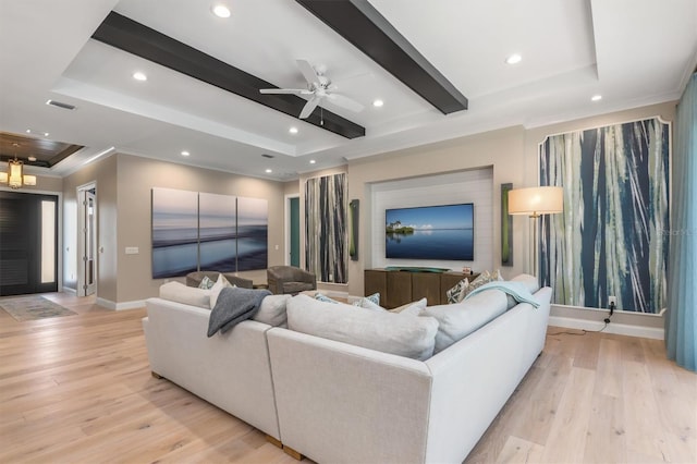 living area with a tray ceiling, beamed ceiling, light wood-type flooring, and visible vents