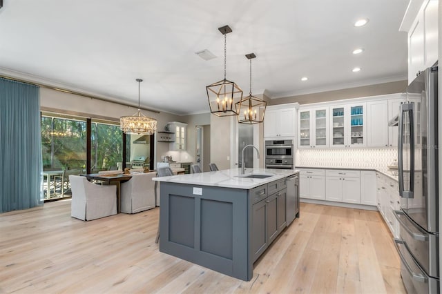 kitchen featuring crown molding, backsplash, appliances with stainless steel finishes, white cabinets, and a sink