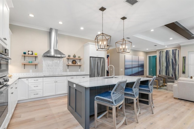 kitchen with a sink, visible vents, appliances with stainless steel finishes, wall chimney range hood, and open shelves