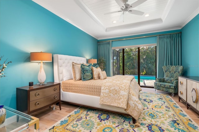 bedroom featuring access to outside, a tray ceiling, wood finished floors, and crown molding