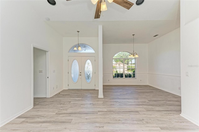 entryway with light wood-type flooring, visible vents, baseboards, and ceiling fan with notable chandelier