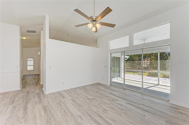 empty room with lofted ceiling, a ceiling fan, baseboards, visible vents, and light wood-style floors