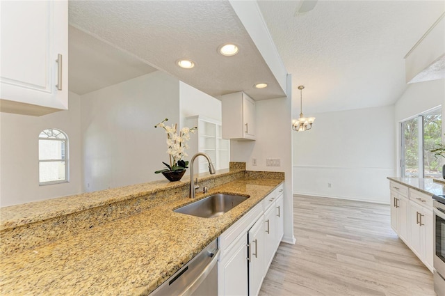 kitchen with white cabinets, light stone countertops, light wood-style floors, and a sink