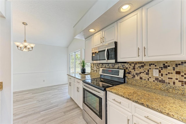 kitchen featuring a textured ceiling, vaulted ceiling, stainless steel appliances, and decorative backsplash