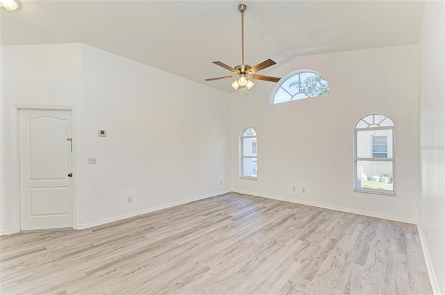 empty room featuring light wood-style floors, lofted ceiling, baseboards, and a ceiling fan