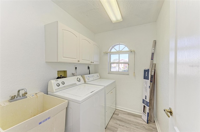 clothes washing area with cabinet space, light wood finished floors, baseboards, separate washer and dryer, and a sink