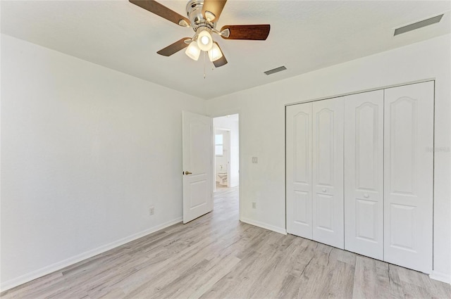 unfurnished bedroom with a closet, light wood-type flooring, visible vents, and baseboards