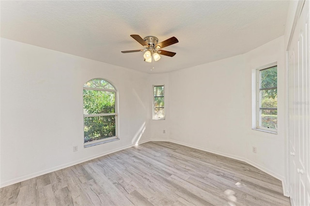 unfurnished room with light wood-style floors, a ceiling fan, baseboards, and a textured ceiling