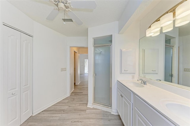 bathroom featuring visible vents, a sink, a shower stall, and wood finished floors