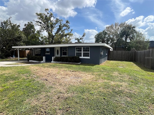 view of front of property with fence, stucco siding, a front lawn, concrete driveway, and a carport