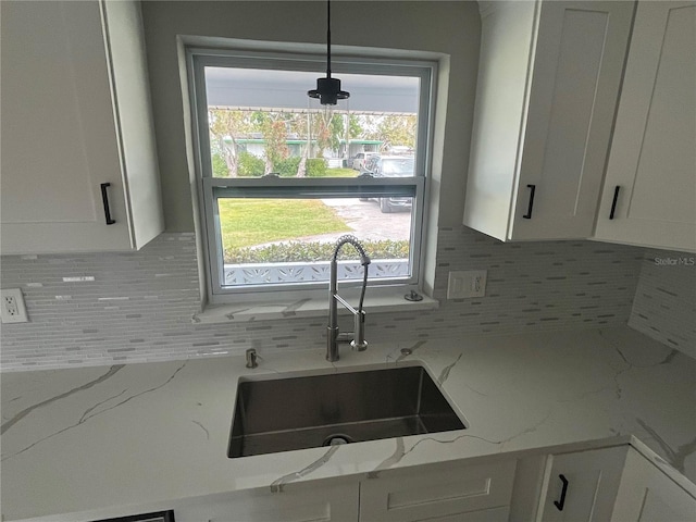 kitchen with a sink, backsplash, and white cabinetry