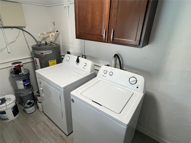 laundry area featuring cabinet space, electric water heater, concrete block wall, and separate washer and dryer