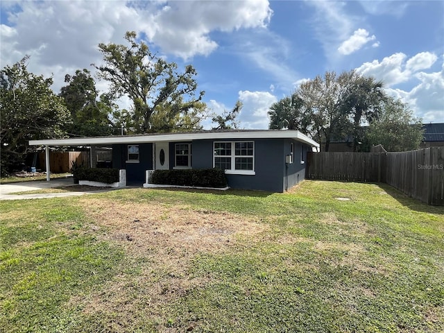 view of front of home featuring stucco siding, a front lawn, fence, concrete driveway, and an attached carport