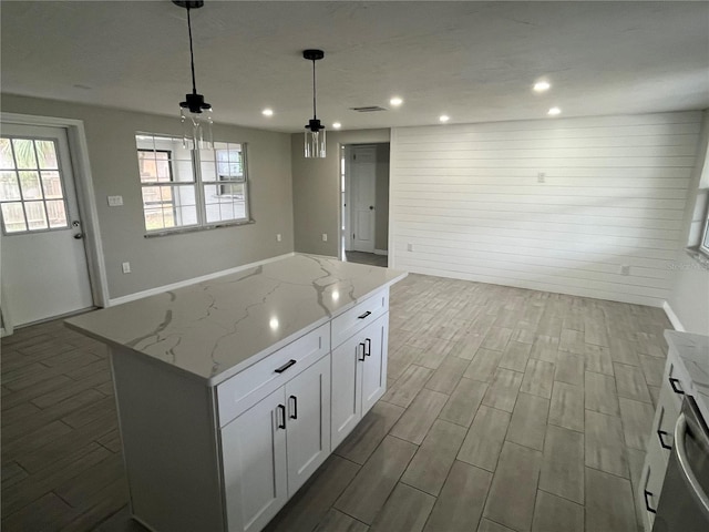 kitchen with a healthy amount of sunlight, white cabinets, a kitchen island, and wood finish floors