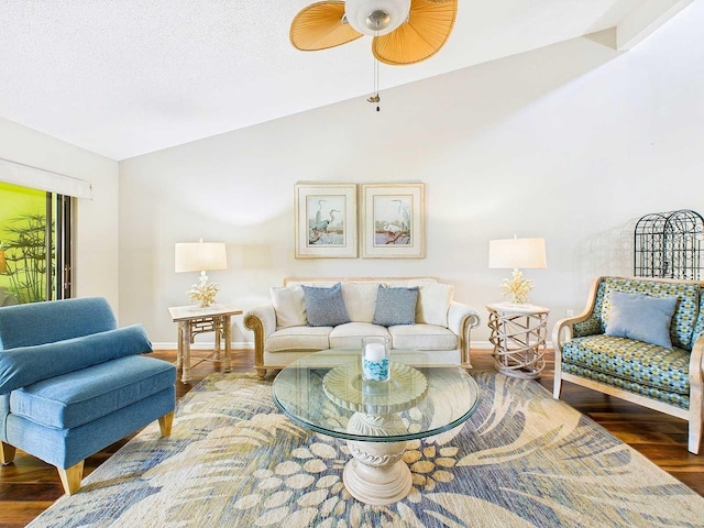 living area featuring lofted ceiling, a textured ceiling, baseboards, and wood finished floors