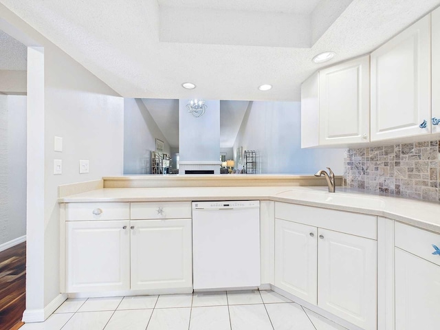 kitchen with decorative backsplash, white dishwasher, light countertops, a textured ceiling, and a sink