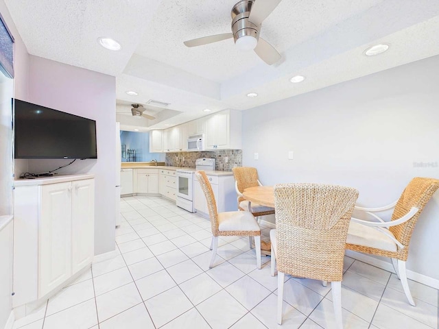 dining room with a raised ceiling, light tile patterned flooring, ceiling fan, and baseboards