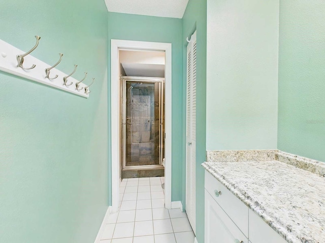 full bath featuring tile patterned flooring, toilet, vanity, baseboards, and a shower stall