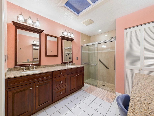 bathroom featuring double vanity, a stall shower, tile patterned flooring, and a sink