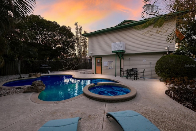 view of pool with a pool with connected hot tub, a patio, and fence