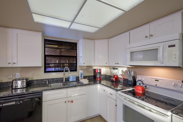 kitchen featuring white cabinets, white appliances, dark stone counters, and a sink