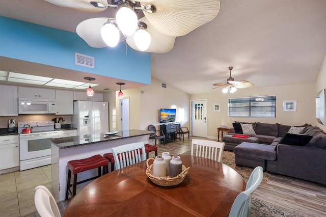 dining room with visible vents, vaulted ceiling, a ceiling fan, and light wood finished floors