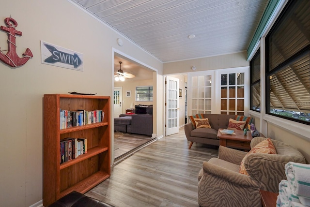 living area with a sunroom, wood finished floors, and ornamental molding