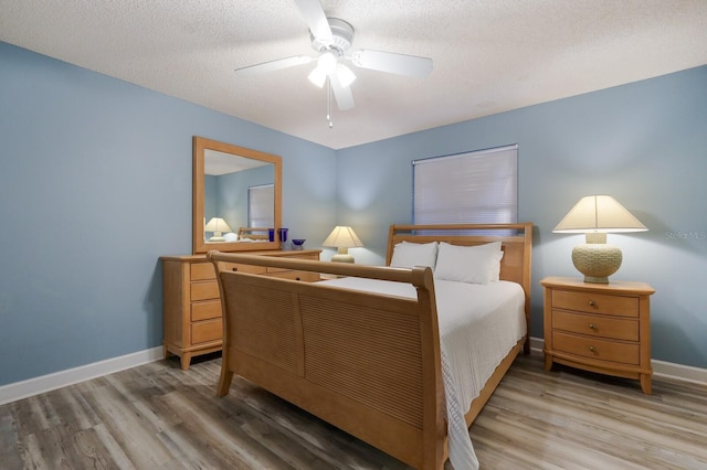 bedroom with wood finished floors, baseboards, and a textured ceiling