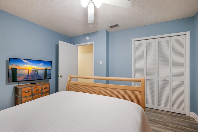 bedroom featuring visible vents, wood finished floors, a closet, a textured ceiling, and a ceiling fan