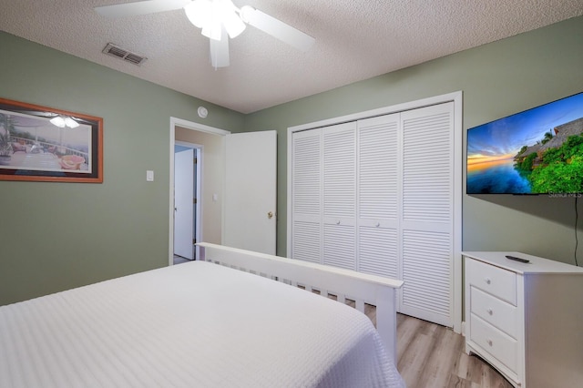 bedroom with a closet, visible vents, light wood-style flooring, and a textured ceiling