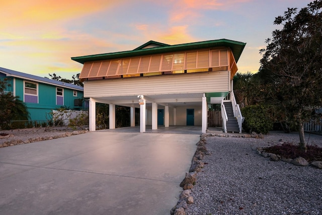 coastal inspired home with stairway, a carport, and concrete driveway