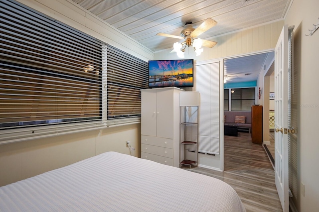 bedroom featuring wooden walls, wood finished floors, and ceiling fan