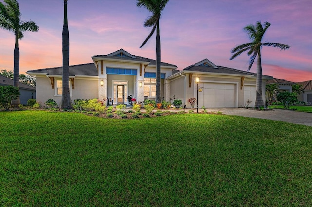 view of front of house with a garage, a yard, decorative driveway, and stucco siding