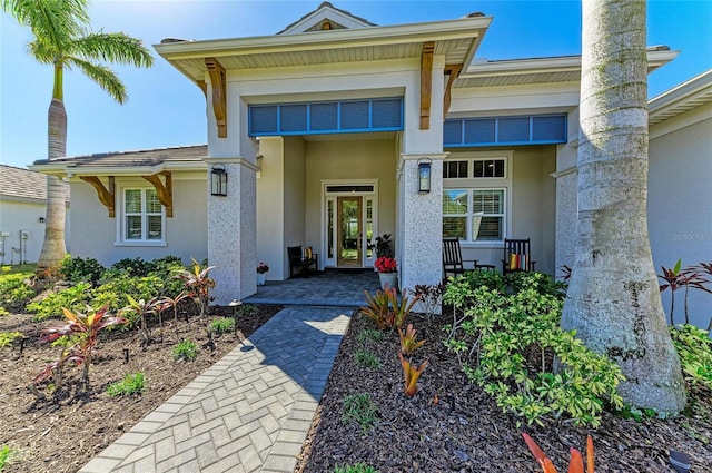 view of exterior entry featuring a porch and stucco siding