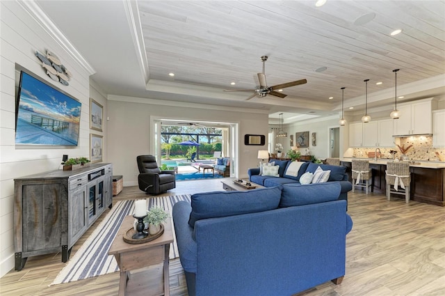 living area with light wood finished floors, wood ceiling, ornamental molding, a tray ceiling, and recessed lighting