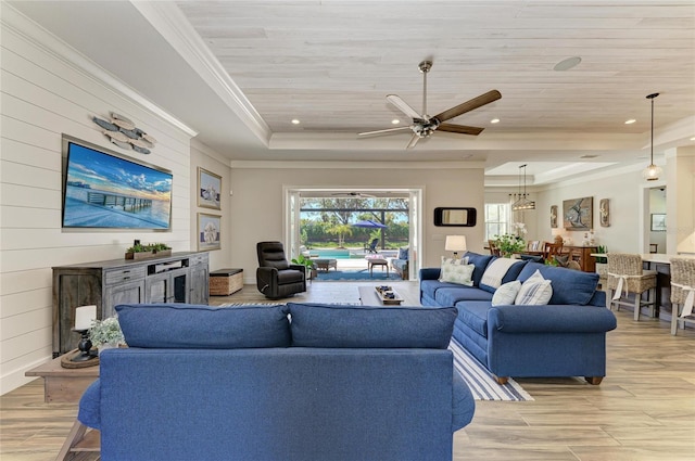 living room featuring wood ceiling, a tray ceiling, light wood-style flooring, and crown molding