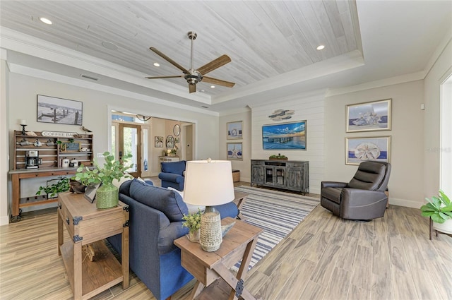 living area with visible vents, wood ceiling, ornamental molding, light wood-type flooring, and a tray ceiling