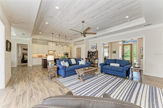 living area with a tray ceiling, visible vents, light wood-style flooring, ornamental molding, and wooden ceiling