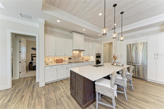 kitchen with stainless steel appliances, light countertops, backsplash, a raised ceiling, and a kitchen bar