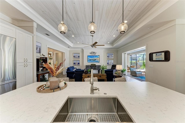 kitchen featuring a raised ceiling, wooden ceiling, stainless steel refrigerator, open floor plan, and a sink