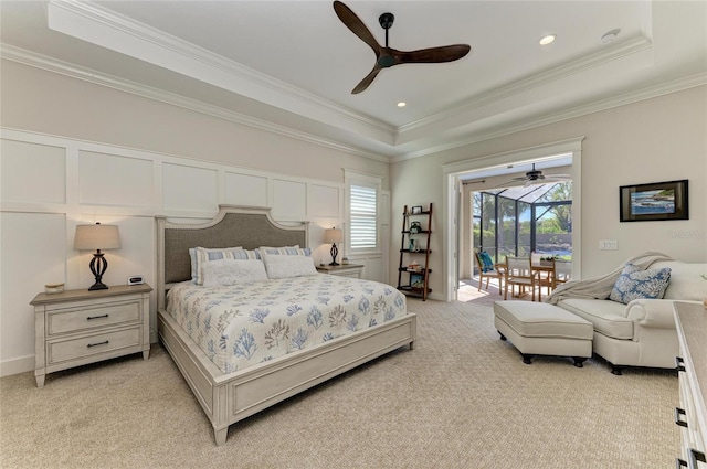 bedroom with a tray ceiling, access to outside, light colored carpet, and a decorative wall