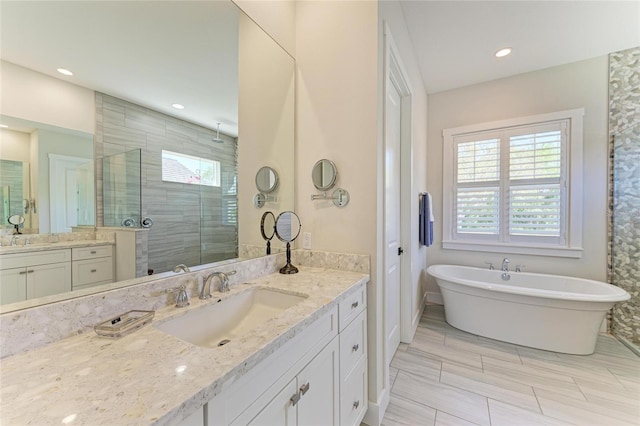 full bath featuring a freestanding tub, a stall shower, two vanities, and a sink