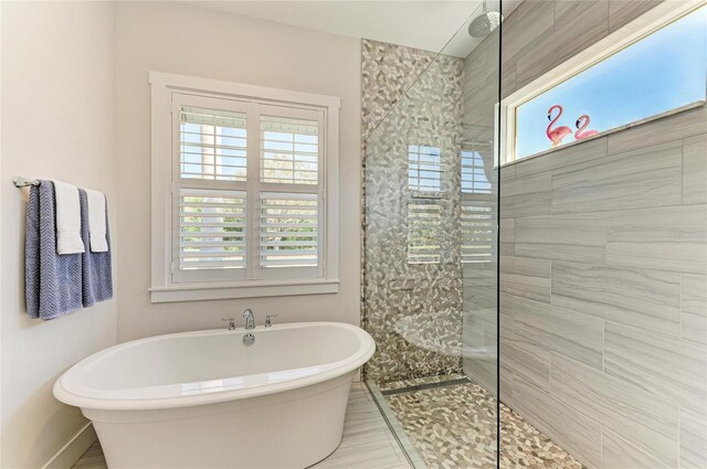 full bathroom with a healthy amount of sunlight, a soaking tub, baseboards, and a walk in shower