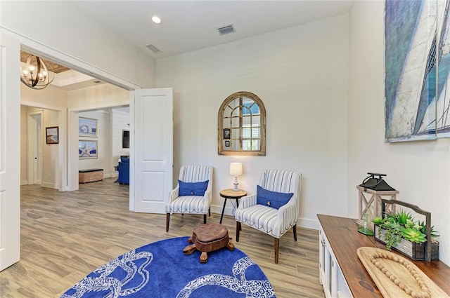 living area with light wood-type flooring, baseboards, visible vents, and a notable chandelier