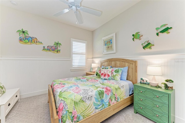 bedroom with wainscoting, a ceiling fan, and light colored carpet