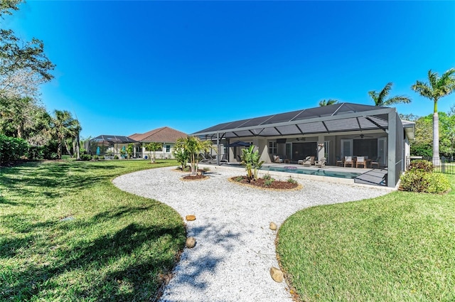 back of house with a lawn, a patio area, ceiling fan, a lanai, and an outdoor pool