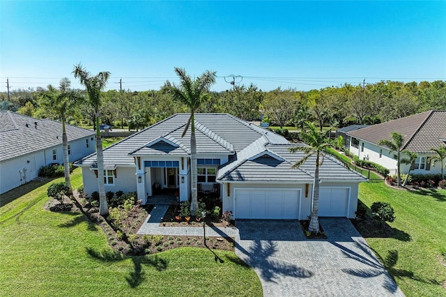 ranch-style house featuring a front lawn, an attached garage, a tile roof, and gravel driveway